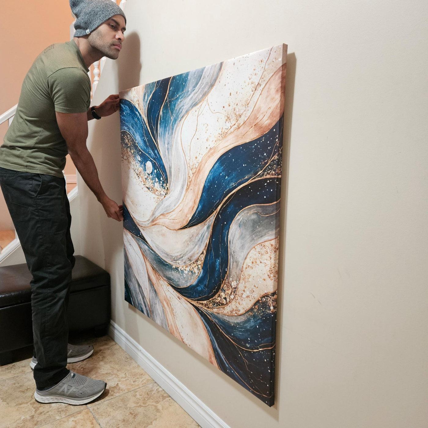 Vivek steadying a large canvas artwork against a wall with both hands