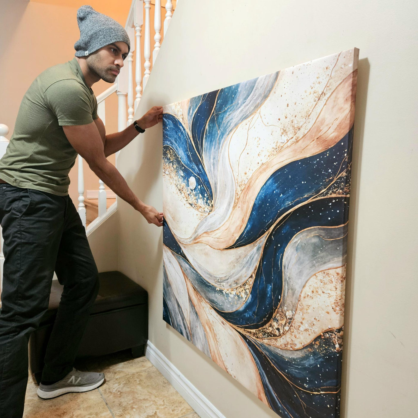 Vivek holding a large canvas artwork flat against a wall