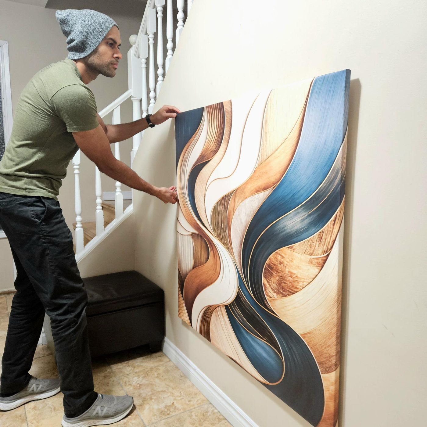 Vivek steadying a large canvas artwork against a wall with both hands